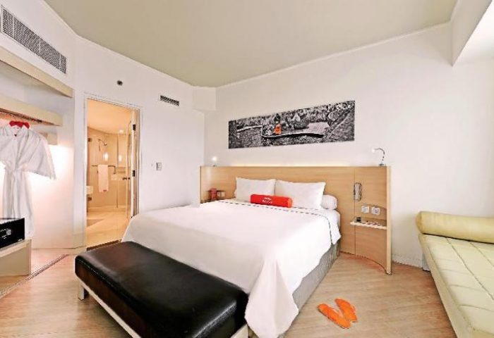 Gay-Friendly HARRIS Hotel Tebet room. Modern design, king bed, en-suite bathroom, robe, and bench. A comfortable stay for gay travelers.
