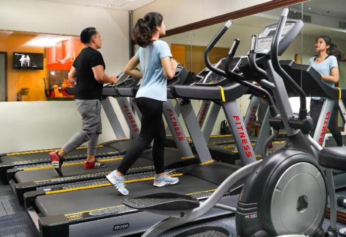 Gym at HARRIS Hotel Tebet, a gay-friendly hotel. Guests work out on treadmills and elliptical machines. Fitness center with modern equipment.