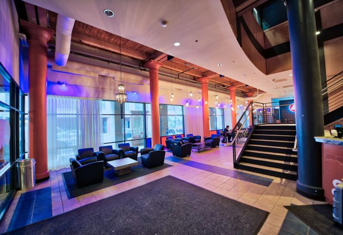 HI Chicago Hostel lobby interior. A gay-friendly hotel with lounge seating, large windows, and a staircase. Modern design.