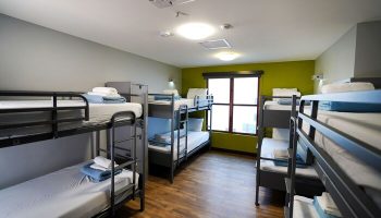 HI Los Angeles Santa Monica Hostel dorm room. Gay-friendly hotel with bunk beds, linens, and a window. Budget travel lodging.