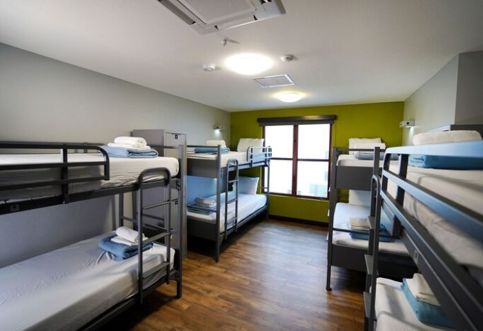 HI Los Angeles Santa Monica Hostel dorm room. Gay-friendly hotel with bunk beds, linens, and a window. Budget travel lodging.