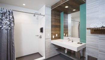 HI Los Angeles Santa Monica Hostel bathroom. Gay-friendly hotel featuring modern sink, shower, and wood accents. Great for gay travelers.