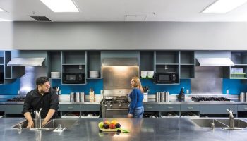 HI Los Angeles Santa Monica Hostel kitchen. Gay-friendly hotel with modern amenities. Guests cooking, sharing meals. Perfect for gay travelers.
