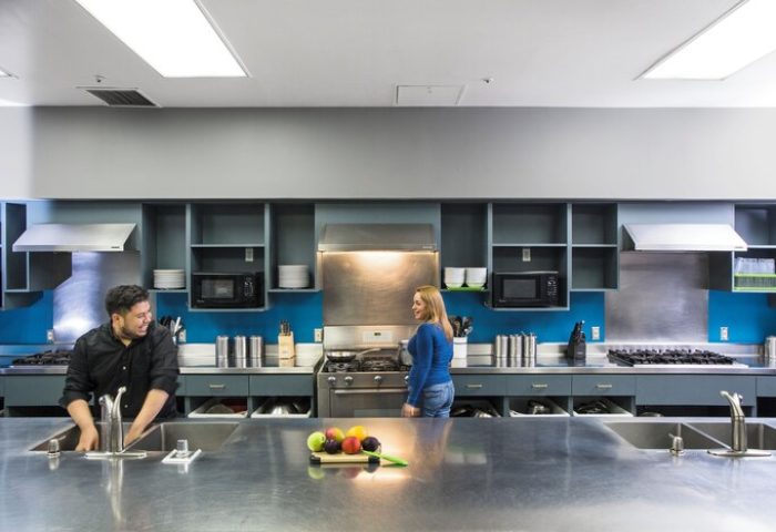 HI Los Angeles Santa Monica Hostel kitchen. Gay-friendly hotel with modern amenities. Guests cooking, sharing meals. Perfect for gay travelers.