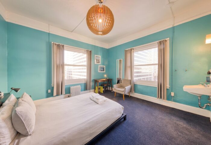 HI San Francisco Downtown Hostel room. Gay-friendly hotel with blue walls, bed, windows, desk, and sink. Hostel for gay men travelers.