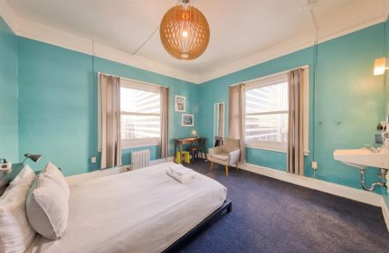 HI San Francisco Downtown Hostel room. Gay-friendly hotel with blue walls, bed, windows, desk, and sink. Hostel for gay men travelers.