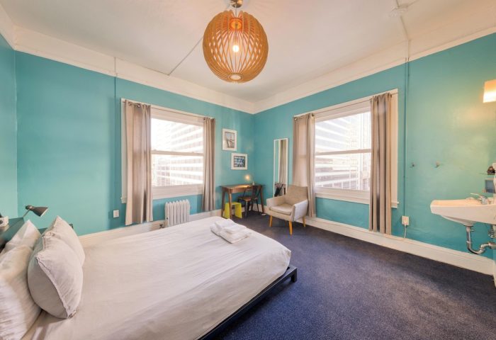 HI San Francisco Downtown Hostel room. Gay-friendly hotel with blue walls, bed, windows, desk, and sink. Hostel for gay men travelers.