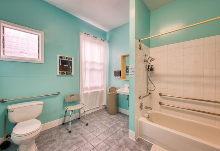 Bathroom at HI San Francisco Downtown Hostel, a gay-friendly hotel. Accessible features include grab bars, shower seat, and toilet.
