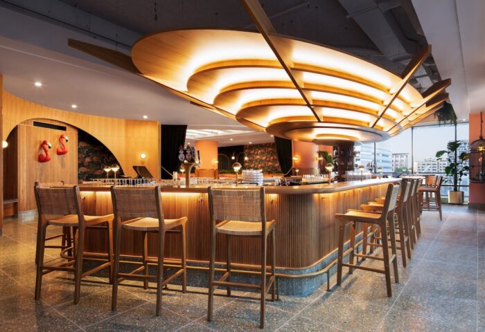 HONEYROSE Hotel, a Tribute Portfolio Hotel, bar area. Gay-friendly hotel in Montreal. Stylish interior, wood bar, stools, and unique lighting.