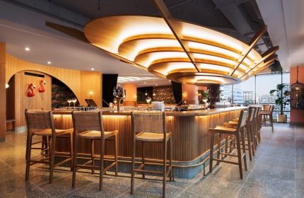 HONEYROSE Hotel, a Tribute Portfolio Hotel, bar area. Gay-friendly hotel in Montreal. Stylish interior, wood bar, stools, and unique lighting.