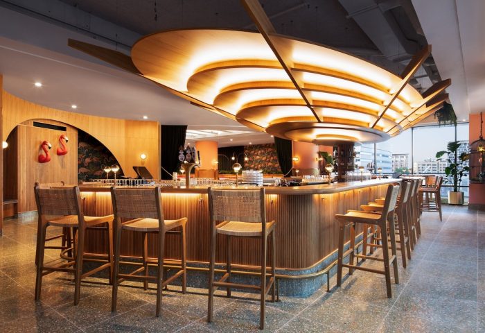 HONEYROSE Hotel, a Tribute Portfolio Hotel, bar area. Gay-friendly hotel in Montreal. Stylish interior, wood bar, stools, and unique lighting.