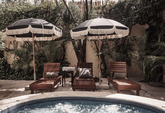 Poolside at Gay-Friendly Hotel Posada 06 Tulum Adults Only. Lounge chairs, umbrellas, and lush greenery create a relaxing, gay travel getaway.