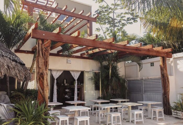 HOTEL POSADA 06 TULUM ADULTS ONLY: Gay-friendly hotel outdoor dining area with wooden pergola, tables, and stools. Tropical plants add to the ambiance.