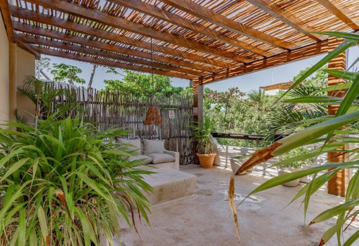 HOTEL POSADA 06 TULUM ADULTS ONLY gay-friendly hotel patio. Outdoor lounge area with plants and a wooden pergola. Tulum travel.