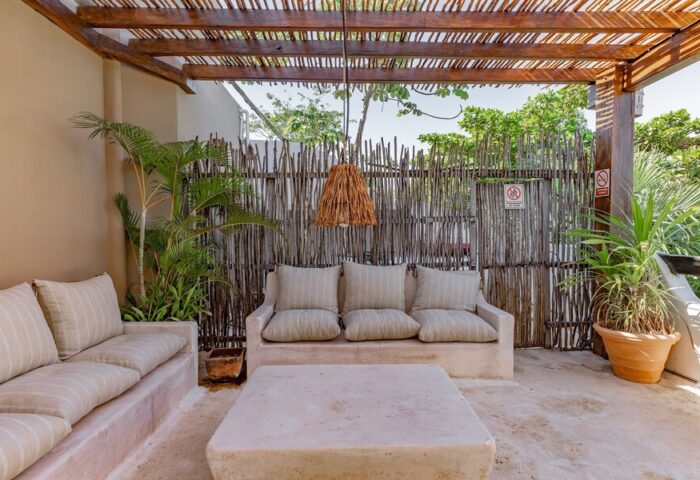 HOTEL POSADA 06 TULUM ADULTS ONLY gay-friendly hotel. Outdoor lounge area with sofas, table, plants, and a rustic wooden pergola.
