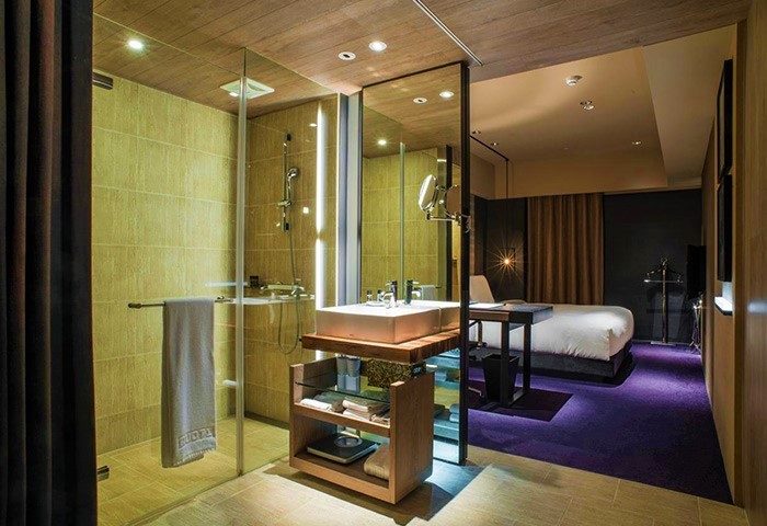 HOTEL QUOTE Taipei gay-friendly hotel room. Modern bathroom with glass shower, sink, and bedroom view. Ideal for gay travelers in Taipei.