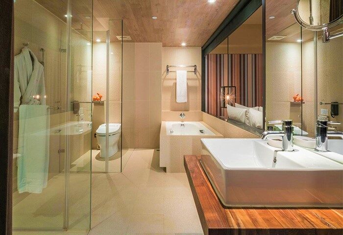 Bathroom at HOTEL QUOTE Taipei, a gay-friendly hotel. Features a glass shower, tub, toilet, and sink with wood counter. Modern design.
