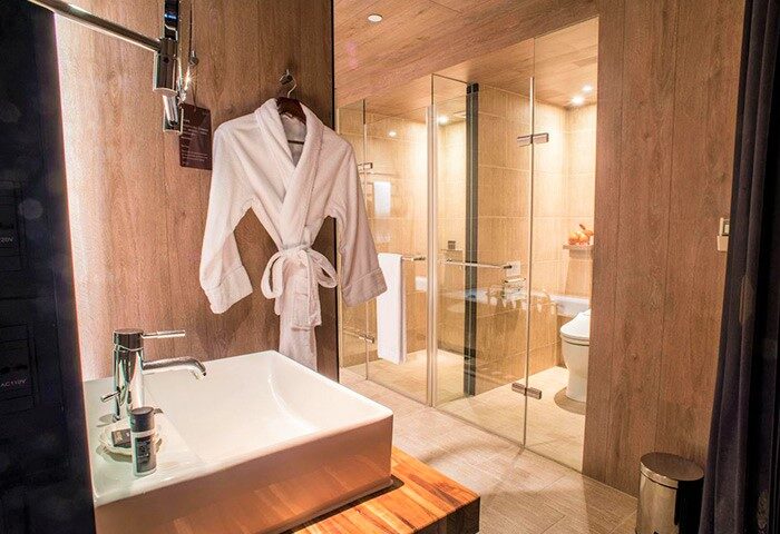 HOTEL QUOTE Taipei bathroom. Gay-friendly hotel room with bathrobe, sink, and glass-enclosed shower. Modern design for gay travelers.