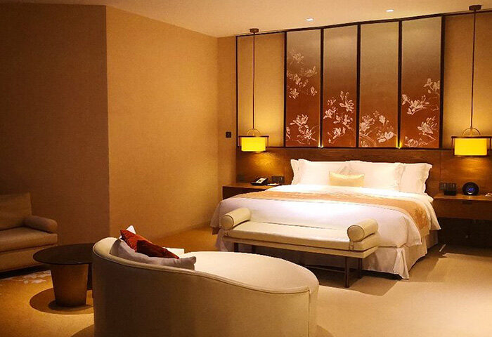 HUALUXE Shanghai Twelve At Hengshan gay-friendly hotel room. Bed with floral headboard and bench. Ideal for gay travelers.