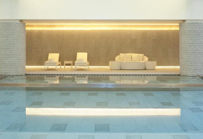 HUALUXE Shanghai Twelve At Hengshan gay-friendly hotel pool. Lounge chairs and a sofa are reflected in the water.