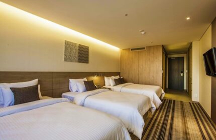 Hamilton Hotel Itaewon triple room. Gay-friendly hotel with three beds, striped carpet, and modern decor. Perfect for gay travel in Seoul, South Korea.