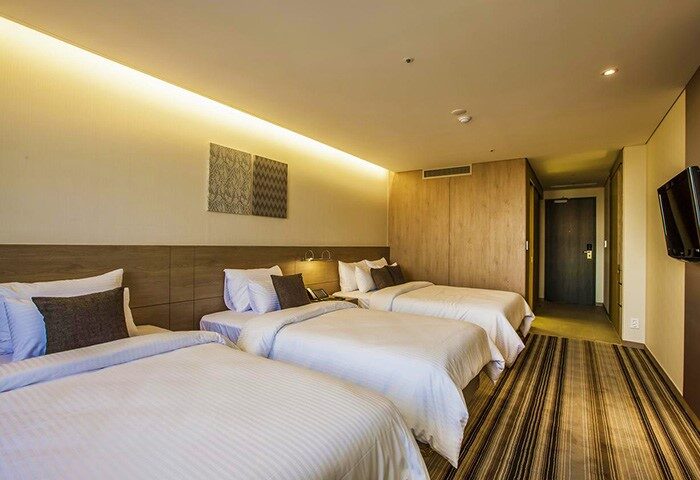 Hamilton Hotel Itaewon triple room. Gay-friendly hotel with three beds, striped carpet, and modern decor. Perfect for gay travel in Seoul, South Korea.