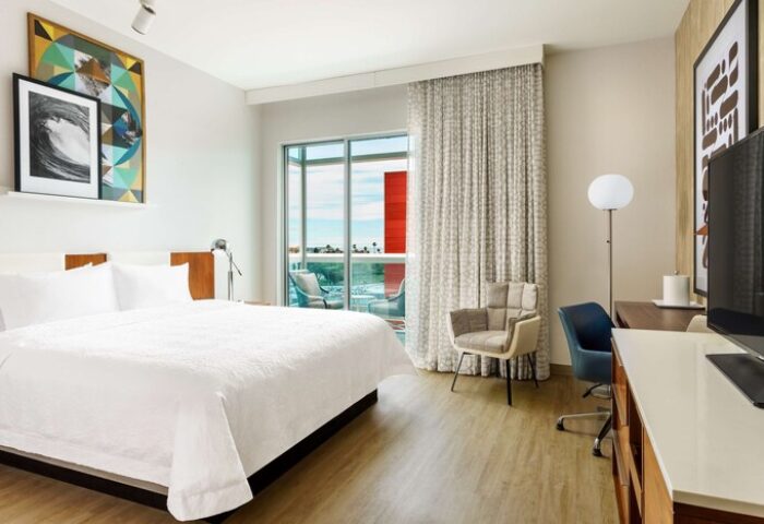 Hampton Inn & Suites Santa Monica guest room. Gay-friendly hotel with balcony, desk, and king bed. Modern decor, art, and comfortable seating.
