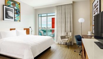 Hampton Inn & Suites Santa Monica guest room. Gay-friendly hotel with balcony, desk, and king bed. Modern decor, art, and comfortable seating.