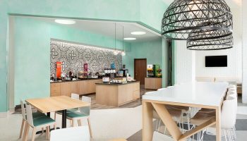 Hampton Inn & Suites Santa Monica breakfast area. Gay-friendly hotel with modern decor, tables, and a breakfast bar. Perfect for gay travelers.