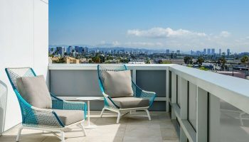 Balcony view at Hampton Inn & Suites, Santa Monica. Gay-friendly hotel with city views, perfect for relaxing. Modern outdoor furniture.