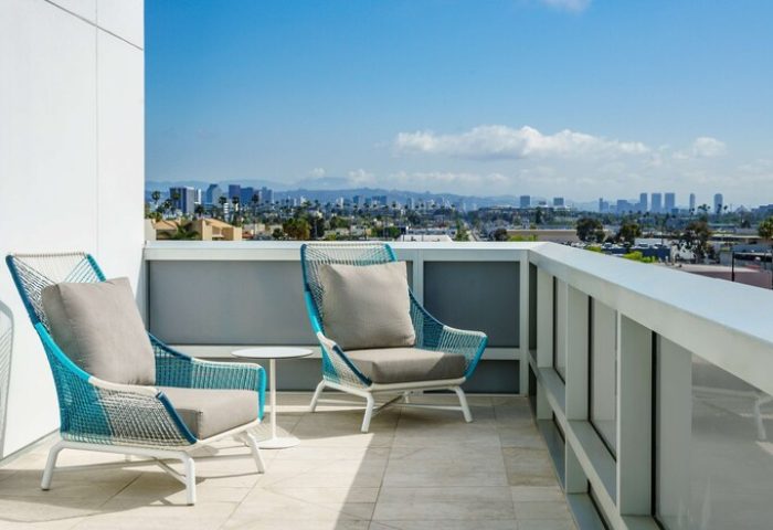 Balcony view at Hampton Inn & Suites, Santa Monica. Gay-friendly hotel with city views, perfect for relaxing. Modern outdoor furniture.