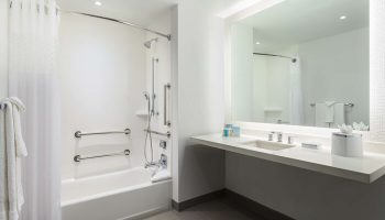 Hampton Inn & Suites Santa Monica bathroom. Gay-friendly hotel with accessible tub, shower, grab bars, and sink. Modern, clean design.