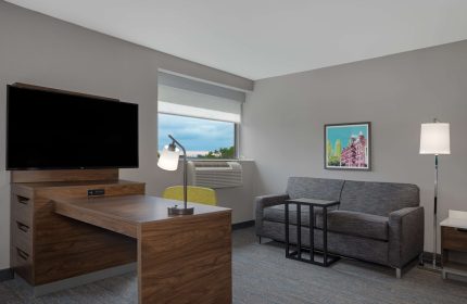 Hampton Inn & Suites by Hilton Toronto Downtown guest room. Desk, TV, sofa, and window. Gay-friendly hotel for gay men travelers.