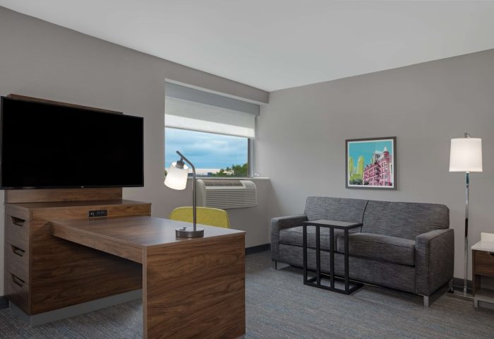 Hampton Inn & Suites by Hilton Toronto Downtown guest room. Desk, TV, sofa, and window. Gay-friendly hotel for gay men travelers.