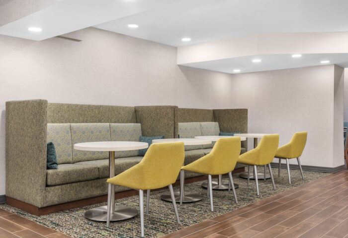 Hampton Inn & Suites by Hilton Toronto Downtown seating area. Gay-friendly hotel with booths, tables, and yellow chairs for guests' comfort.
