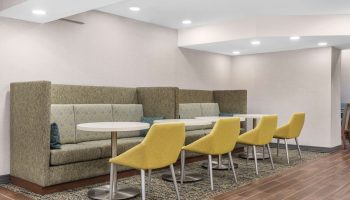 Hampton Inn & Suites by Hilton Toronto Downtown seating area. Gay-friendly hotel with booths, tables, and yellow chairs for guests' comfort.