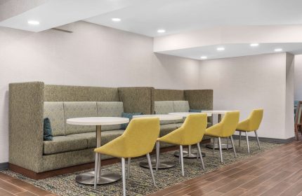 Hampton Inn & Suites by Hilton Toronto Downtown seating area. Gay-friendly hotel with booths, tables, and yellow chairs for guests' comfort.
