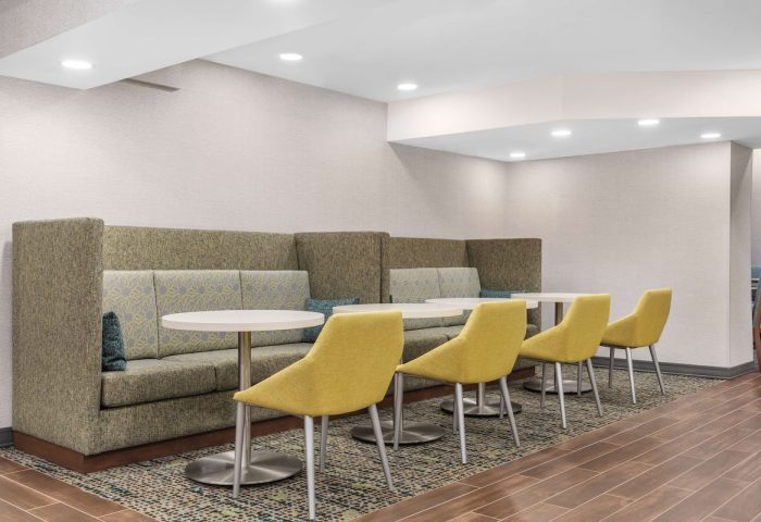 Hampton Inn & Suites by Hilton Toronto Downtown seating area. Gay-friendly hotel with booths, tables, and yellow chairs for guests' comfort.