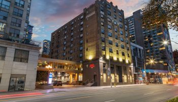 Exterior of Hampton Inn & Suites by Hilton Toronto Downtown, a gay-friendly hotel for gay men, at dusk.
