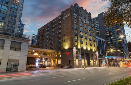 Exterior of Hampton Inn & Suites by Hilton Toronto Downtown, a gay-friendly hotel for gay men, at dusk.