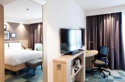 Hampton by Hilton Berlin City East Side Gallery room. Pet-friendly, gay-friendly hotel with bed, TV, desk, and chair. Modern design for a comfortable stay.