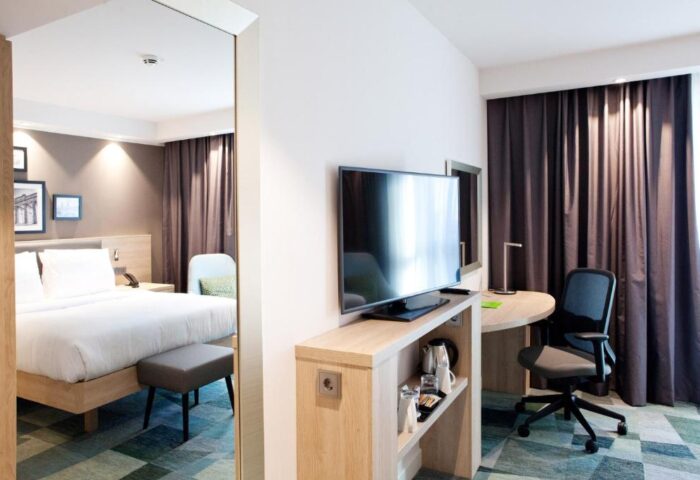 Hampton by Hilton Berlin City East Side Gallery room. Pet-friendly, gay-friendly hotel with bed, TV, desk, and chair. Modern design for a comfortable stay.