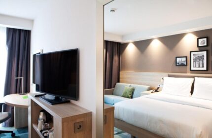 Hampton by Hilton Berlin City East Side Gallery room. Pet-friendly, gay-friendly hotel with TV, bed, and sofa. Modern interior design.
