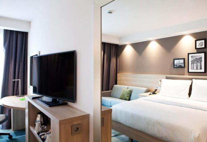 Hampton by Hilton Berlin City East Side Gallery room. Pet-friendly, gay-friendly hotel with TV, bed, and sofa. Modern interior design.