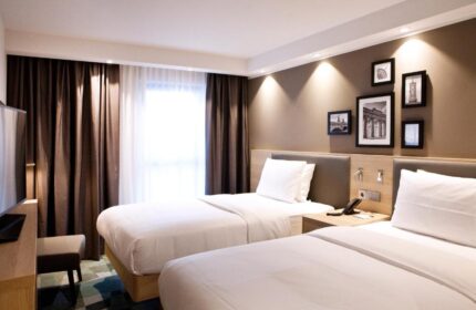 Hampton by Hilton Berlin City East Side Gallery: Gay-friendly, pet-friendly hotel room with twin beds, brown curtains, and framed pictures on the wall.