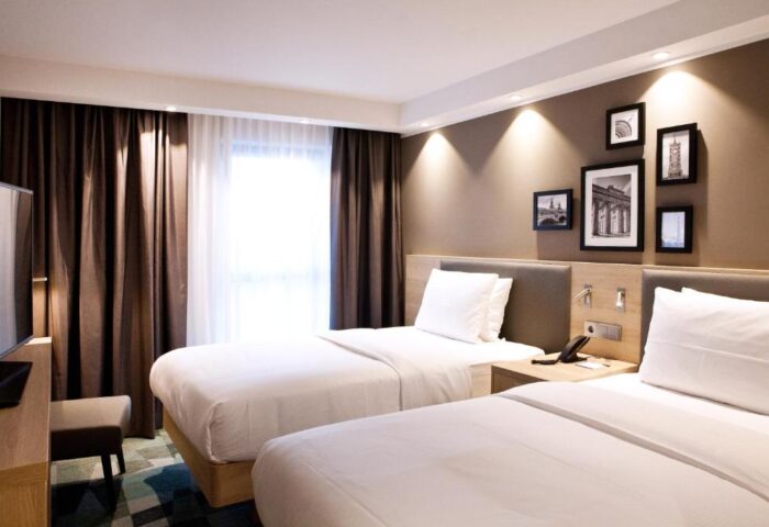 Hampton by Hilton Berlin City East Side Gallery: Gay-friendly, pet-friendly hotel room with twin beds, brown curtains, and framed pictures on the wall.