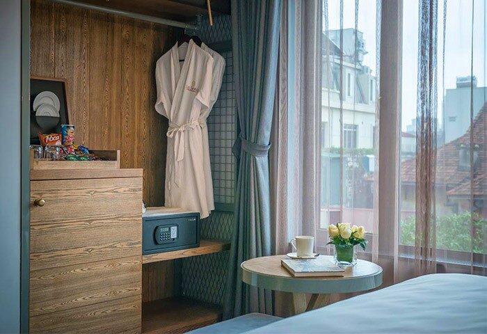 Hanoi La Siesta Hotel Trendy room detail. Bathrobes in closet, snacks, safe, table with flowers, and city view. Gay-friendly hotel.