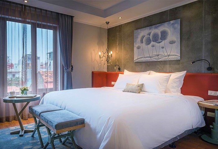 Hanoi La Siesta Hotel Trendy bedroom. Gay-friendly hotel room with king bed, bench, and city view. Modern design for gay travelers in Hanoi.