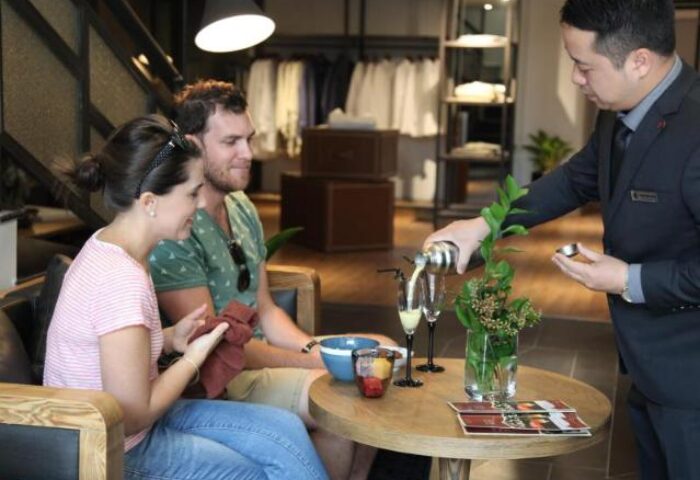 Hanoi La Siesta Hotel Trendy: A gay-friendly hotel in Hanoi, Vietnam. Bartender pouring drinks for a couple in the hotel lobby.