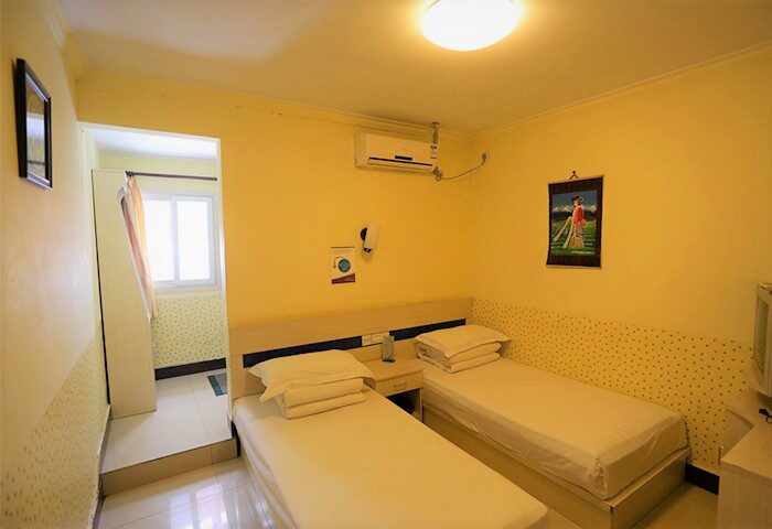 Happy Dragon Backpackers Hostel room. Gay-friendly hotel with twin beds, yellow walls, and air conditioning. Budget travel for gay men.
